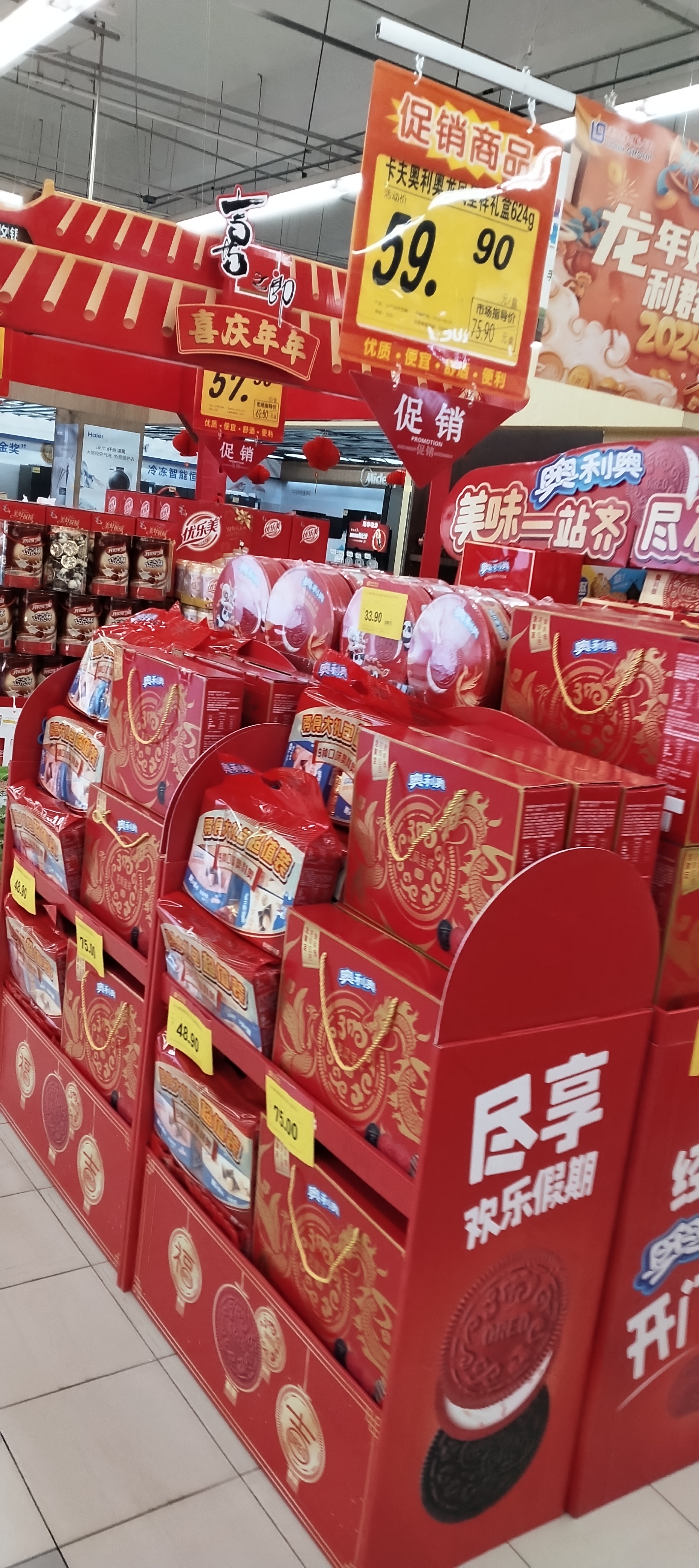 在一个繁华的城市中，有一家大型超市。这家超市的货架上摆满了各种各样的商品，从新鲜的蔬菜到美味的零食，应有尽有。此外，超市里还挂着一些红色的灯笼，为整个空间增添了节日氛围。在收银台前，顾客们正在排队结账