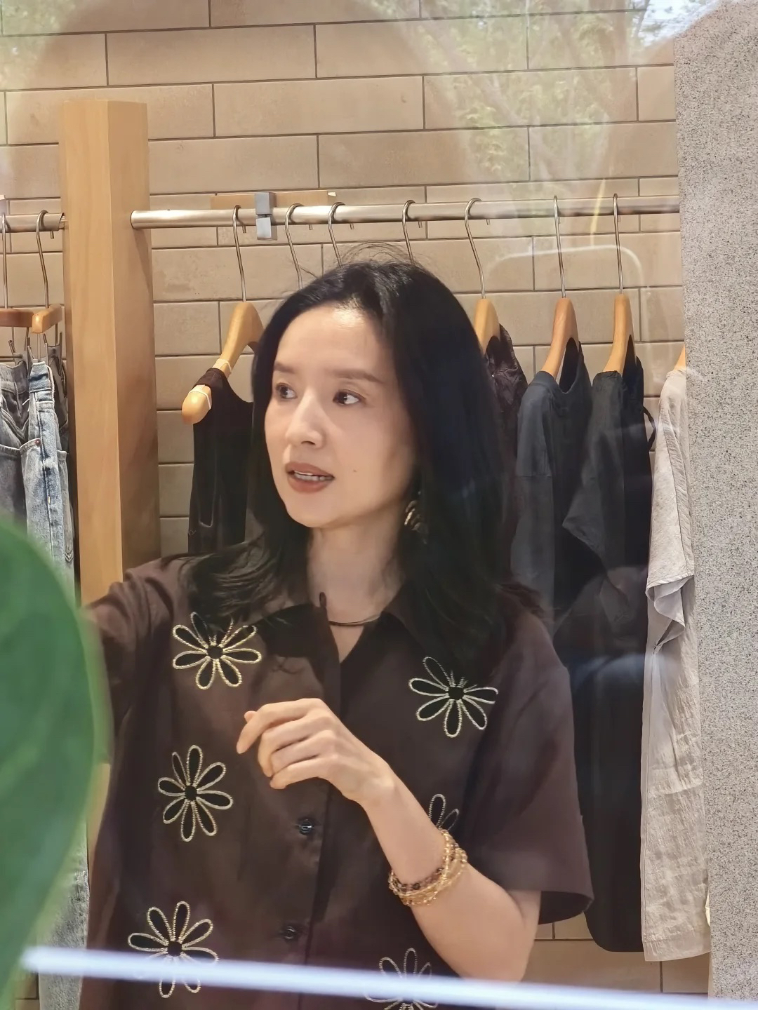 路人镜头中的董洁好漂亮啊！
她真的很适合这种素雅的穿搭和妆容，不需要太花哨，就给人一种冷清优雅的感觉！
这次就选择了一件咖色的短袖衬衫，上面是刺绣印花的图案增加细节感。
金色的大耳饰和衣服上的图案相呼