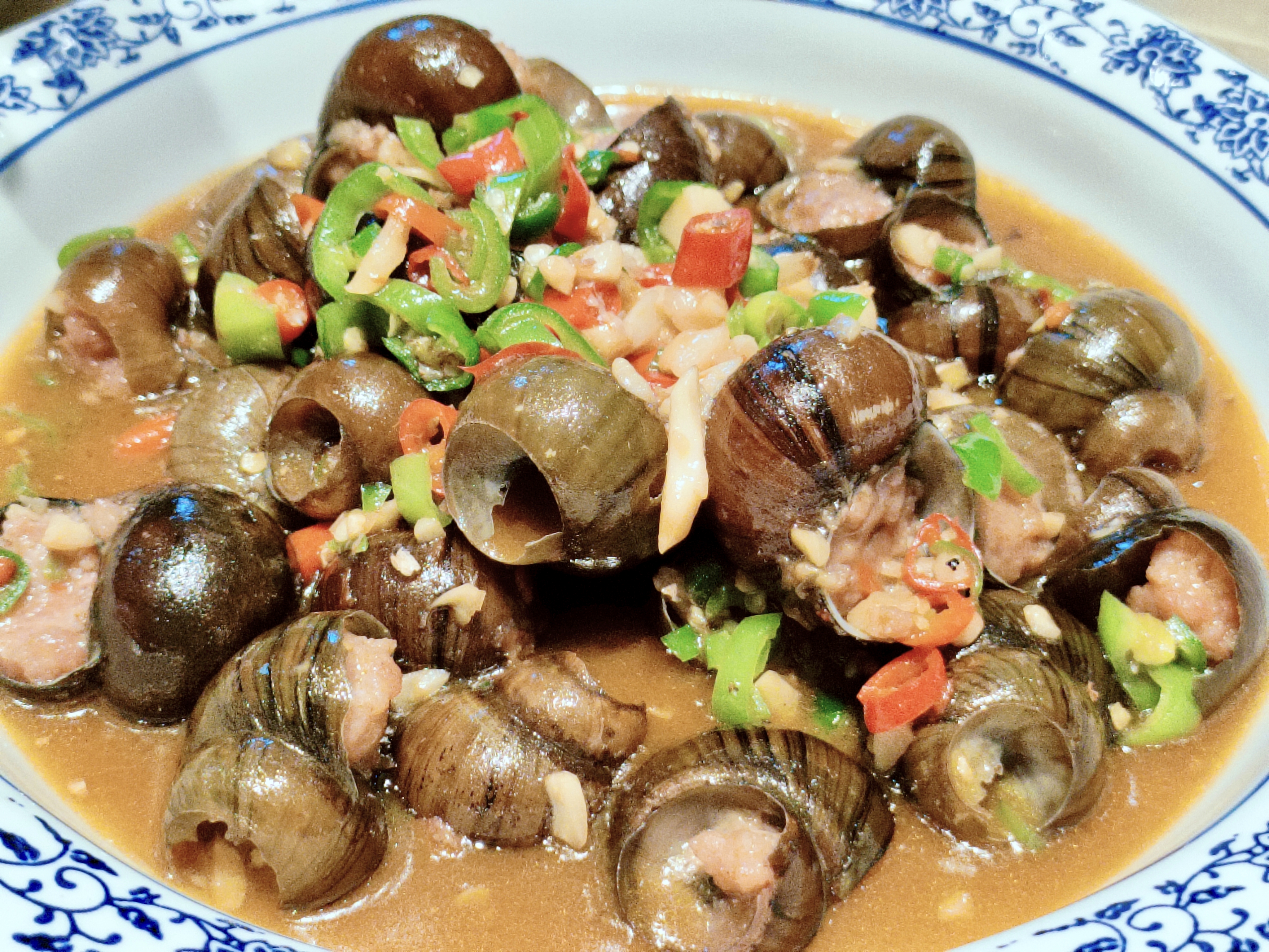 #美食之乡铅山# 【江西小炒:螺丝煲】选取大个田螺，剪去田螺屁股，挑出螺蛳肉，混合瘦肉泥，再塞回田螺壳进行烧制。#在铅山遇见辛弃疾# #我为上饶上大分#