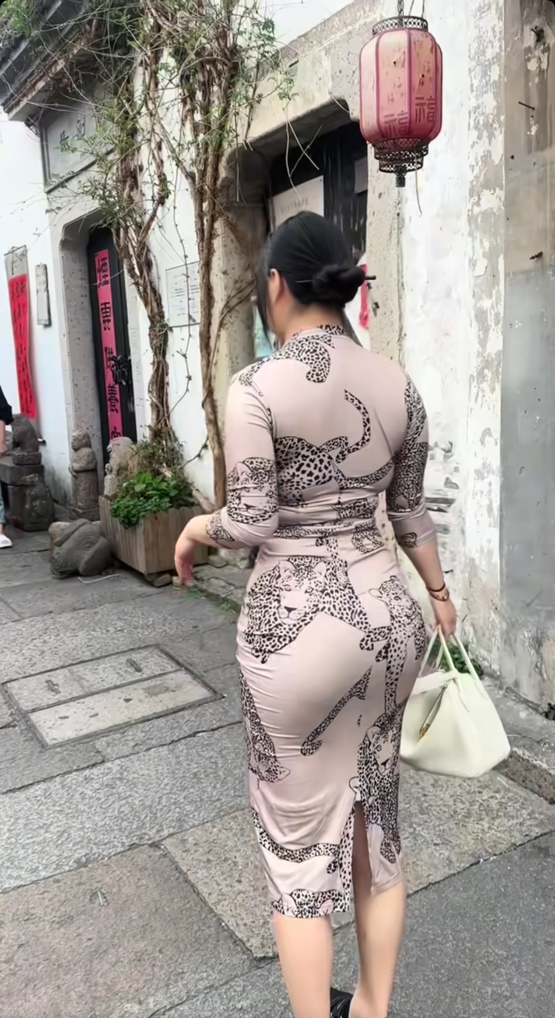在古旧街巷，旗袍勾勒曲线，豹纹添了几分张扬。白墙、红灯笼作陪，传统与时尚碰撞，每一步都似在诉说：古典韵味里，也能活出热烈的自我 。